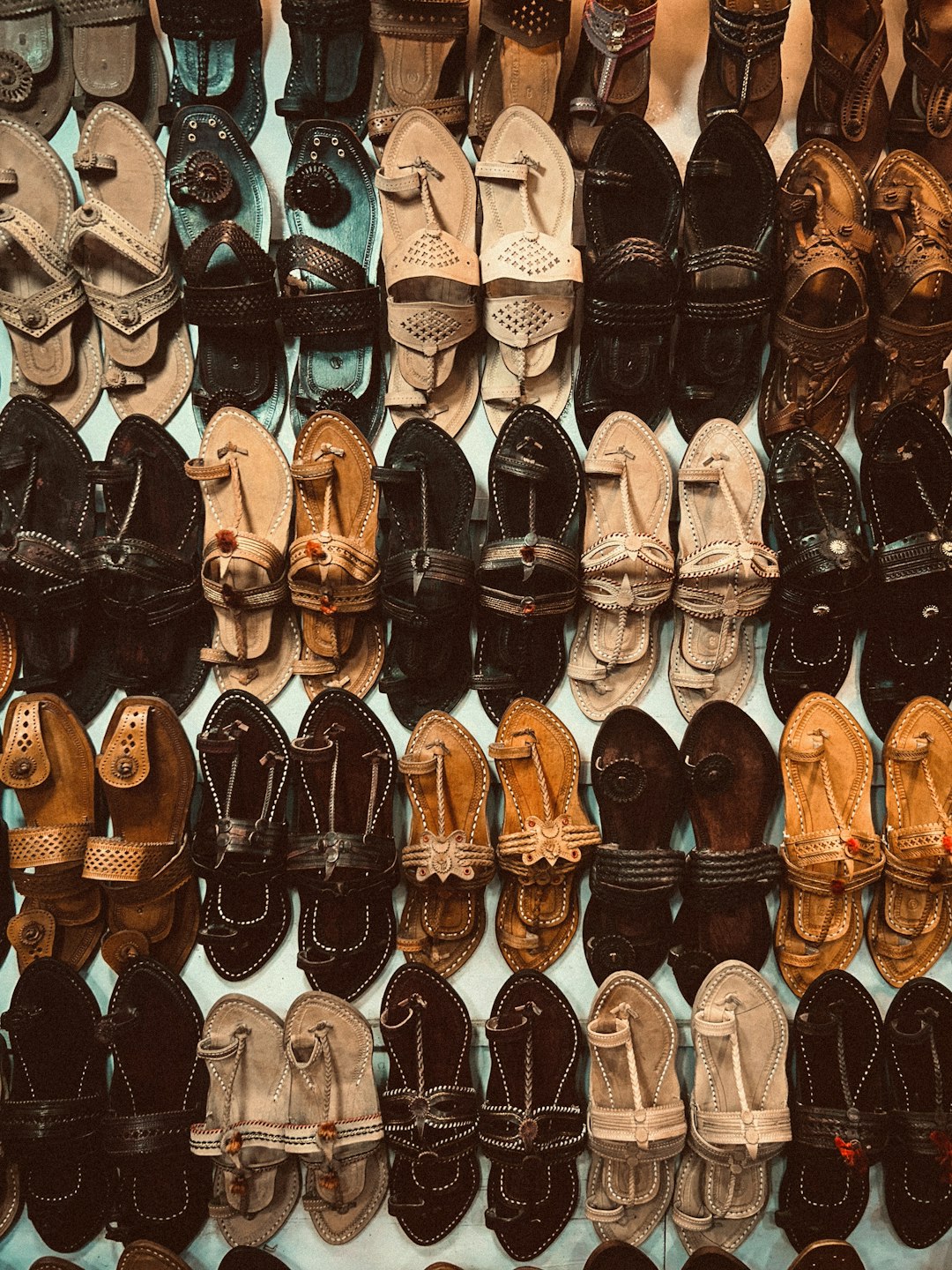 A pair of tan Kolhapuri chappals on a wooden surface