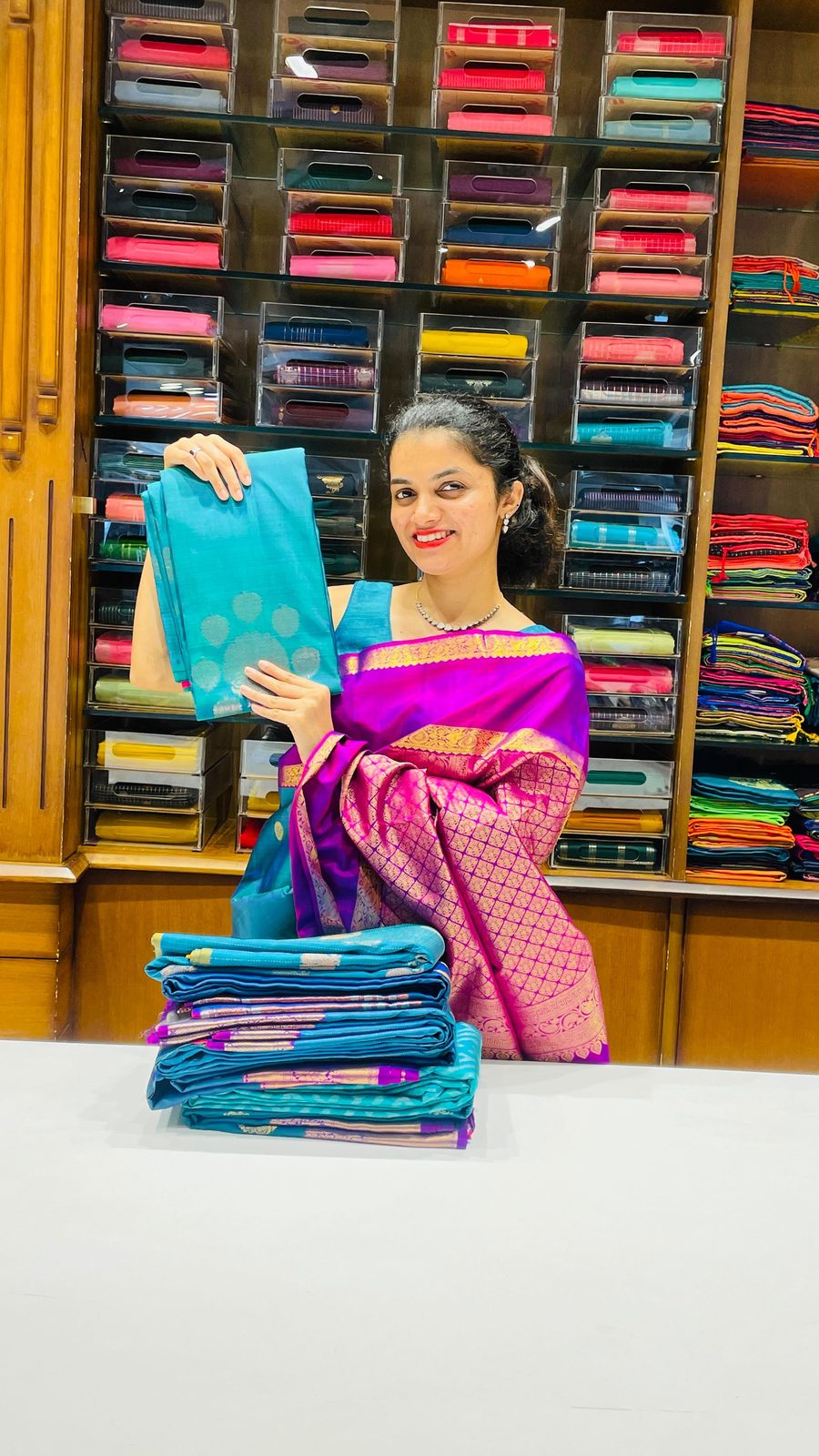 Model in a teal cotton-silk saree holding a pink dupatta inside the Shasthas store