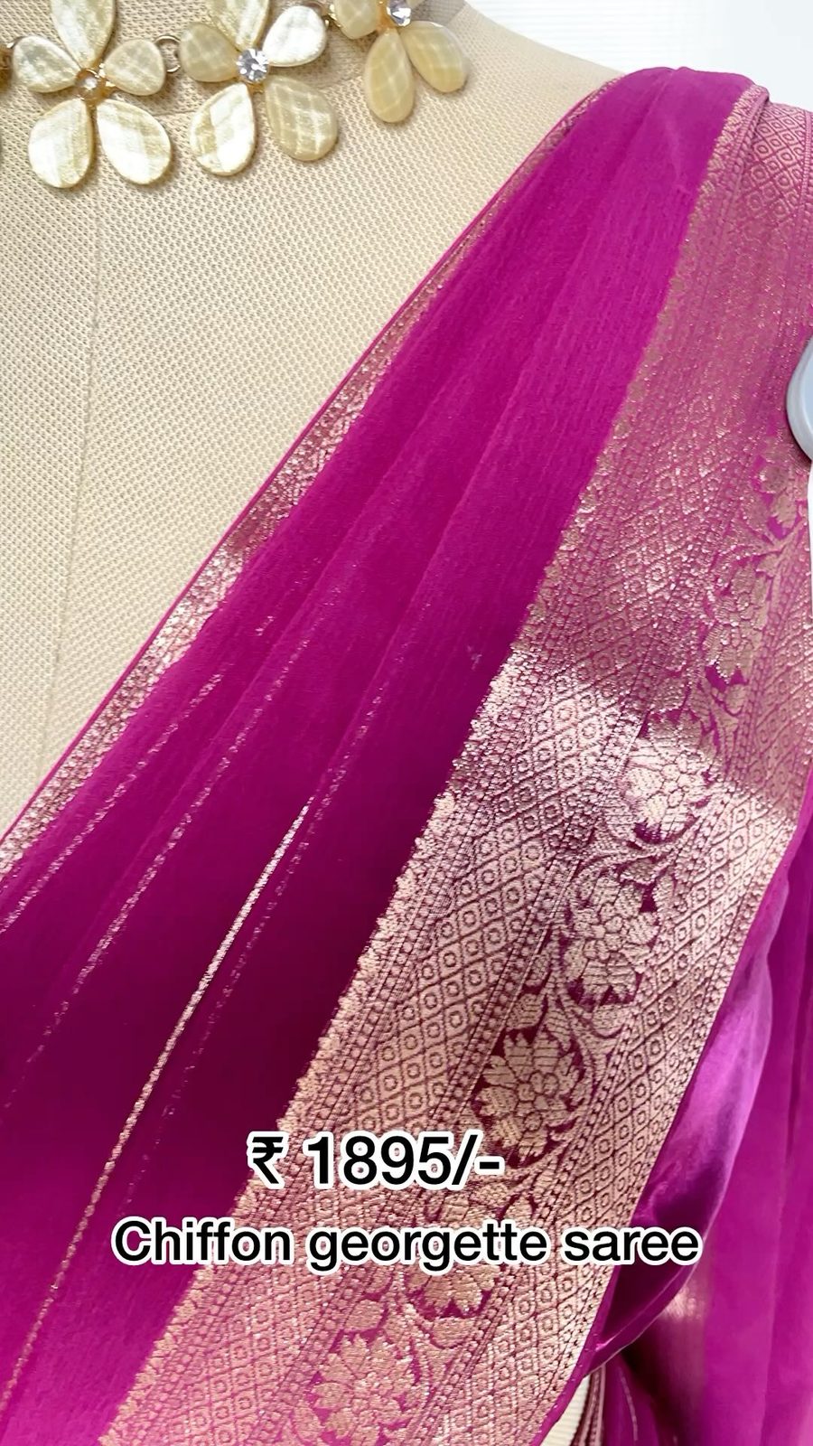 Folded peacock-tone tissue georgette saree with silver zari border on a white surface